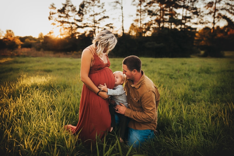 Wellsville NY Family & Newborn Photographer, family of three, little boy kissing mother's belly