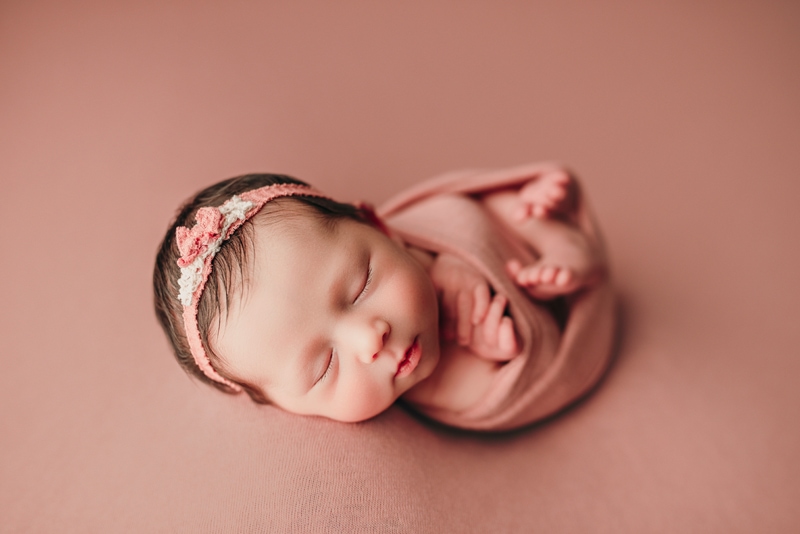 Wellsville NY Family & Newborn Photographer, sleeping baby in headband on blush colored fabric