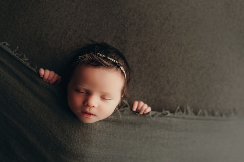 Wellsville NY Family & Newborn Photographer, baby sleeping in between two pieces of dark grey material