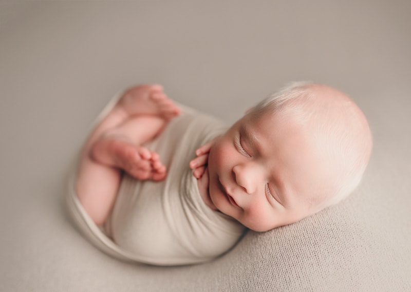 Wellsville NY Family & Newborn Photographer, baby curled up in a cream colored swaddle
